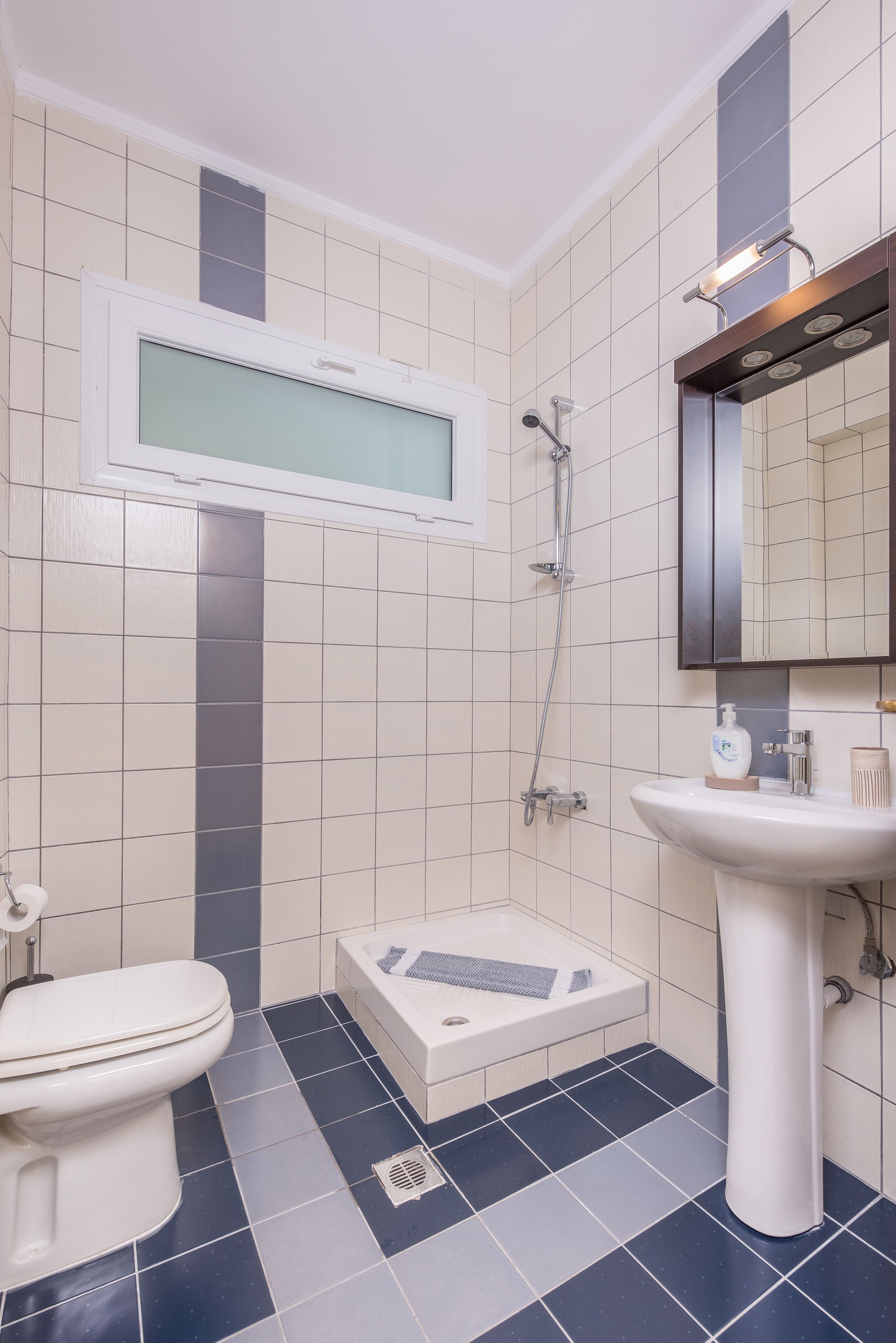 Un baño con inodoro, lavamanos, ducha y espejo.