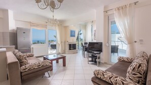 A spacious living area with a sofa set, a television, and a fireplace. - Villas F & B Summer Collection - Aegean Residence (Kassandra)
