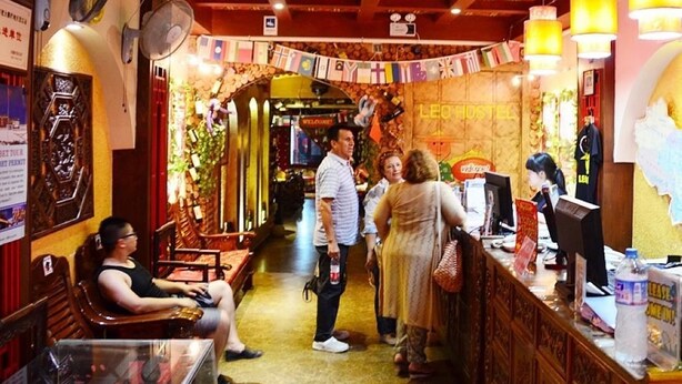 A restaurant interior with wooden furniture, a reception desk, and a 'Welcome' sign. - Leo Hostel (Beijing)