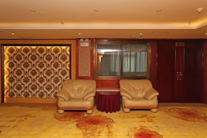 A room with two leather armchairs, a small table, and a patterned wall.