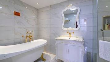 A bathroom with a freestanding bathtub, a vanity with a mirror, and marble tiles.