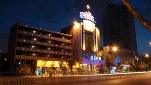 A hotel with a prominent neon sign, multiple floors, and a parking structure. - Lotus Hotel (Kunming)