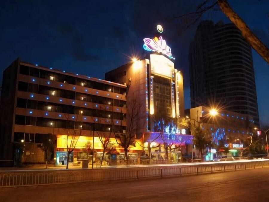 A hotel with a prominent neon sign, multiple floors, and a parking structure.