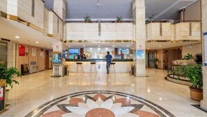 A hotel lobby with a central reception desk, multiple seating areas, and a decorative floor pattern. - Lotus Hotel (Kunming)