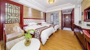 A hotel room with a large bed, a sofa, a small table with a vase, and a bathroom visible through an open door. - Jingxin International Hotel Guilin (Guilin)