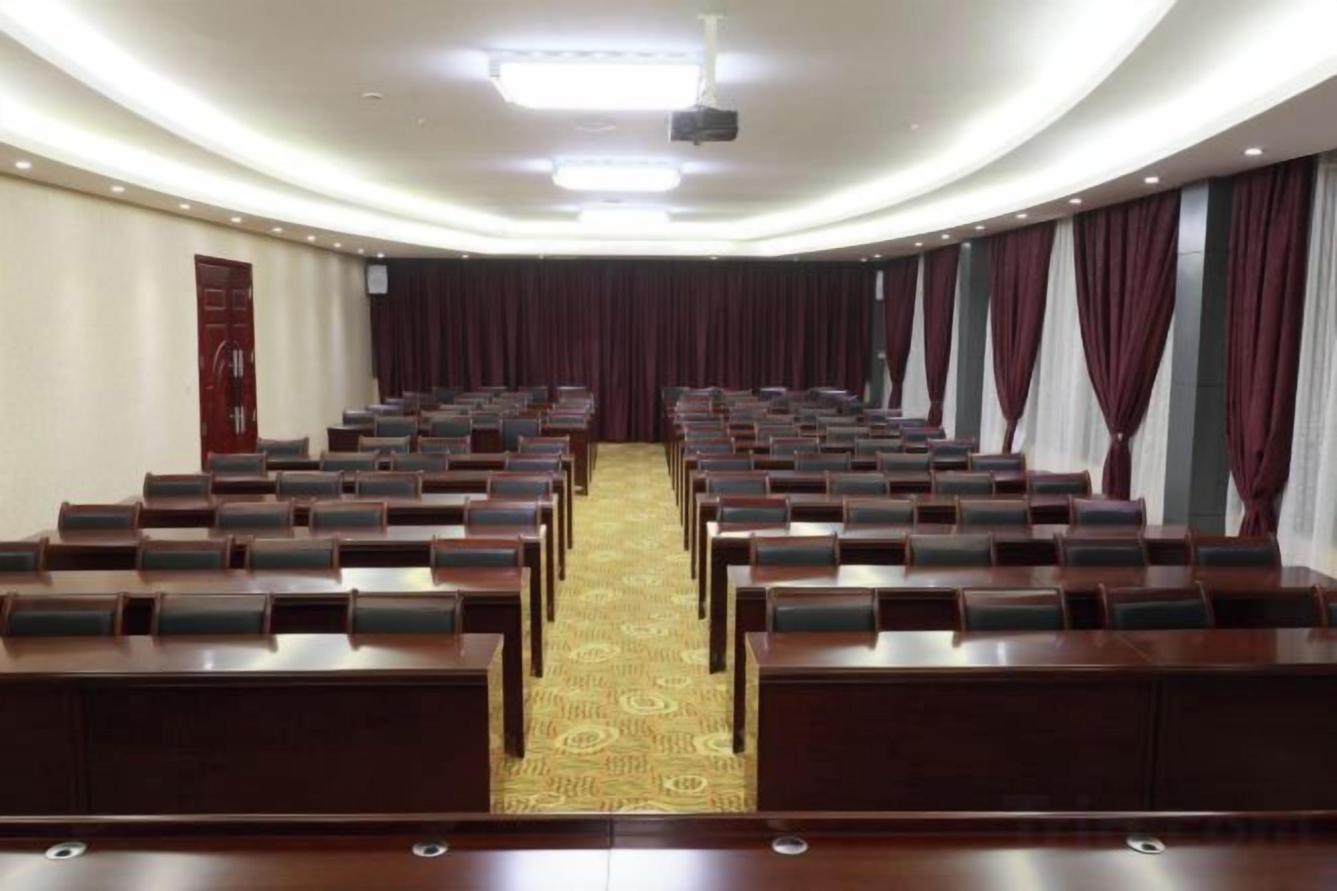 A conference room with rows of chairs, a podium, and a carpeted floor.