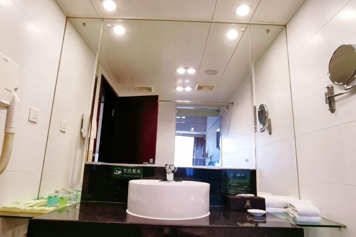 Ein Badezimmer mit großem Spiegel, Waschbecken, Handtuchhalter und Toilette.