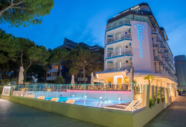 A hotel with a pool area, multiple balconies, and a sign reading "GRAND PLAZA".