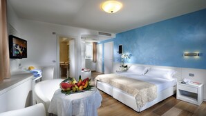 Ein modernes Hotelzimmer mit einem Bett, einem Nachttisch und einem runden Tisch mit Obst.