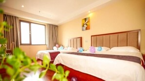 A hotel room with two beds, a large window, and a painting on the wall. - GreenTree Inn Nantong Haimen Bus Statian Shell  Hotel (Nantong)