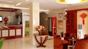 A hotel lobby with a reception desk, seating area, and a decorative vase on a table. - GreenTree Inn Nantong Haimen Bus Statian Shell  Hotel (Nantong)