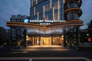 A modern hotel entrance with illuminated signage and a covered walkway. - Holiday Inn Express Qionghai City Center by IHG (Qionghai)