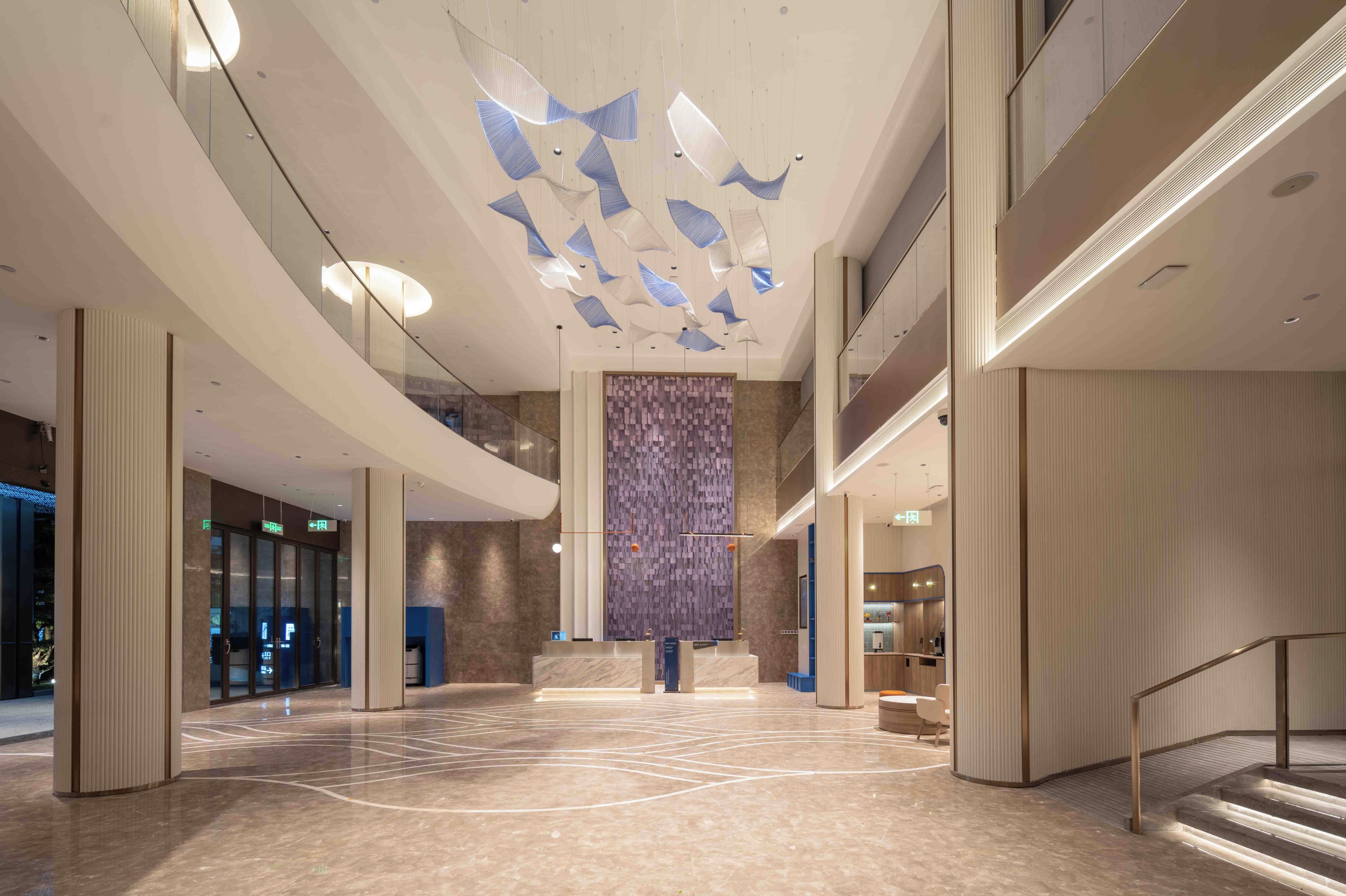 A spacious lobby with a high ceiling, a central column, and a patterned wall.