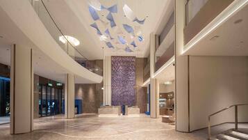 A spacious lobby with a high ceiling, a central column, and a patterned wall.