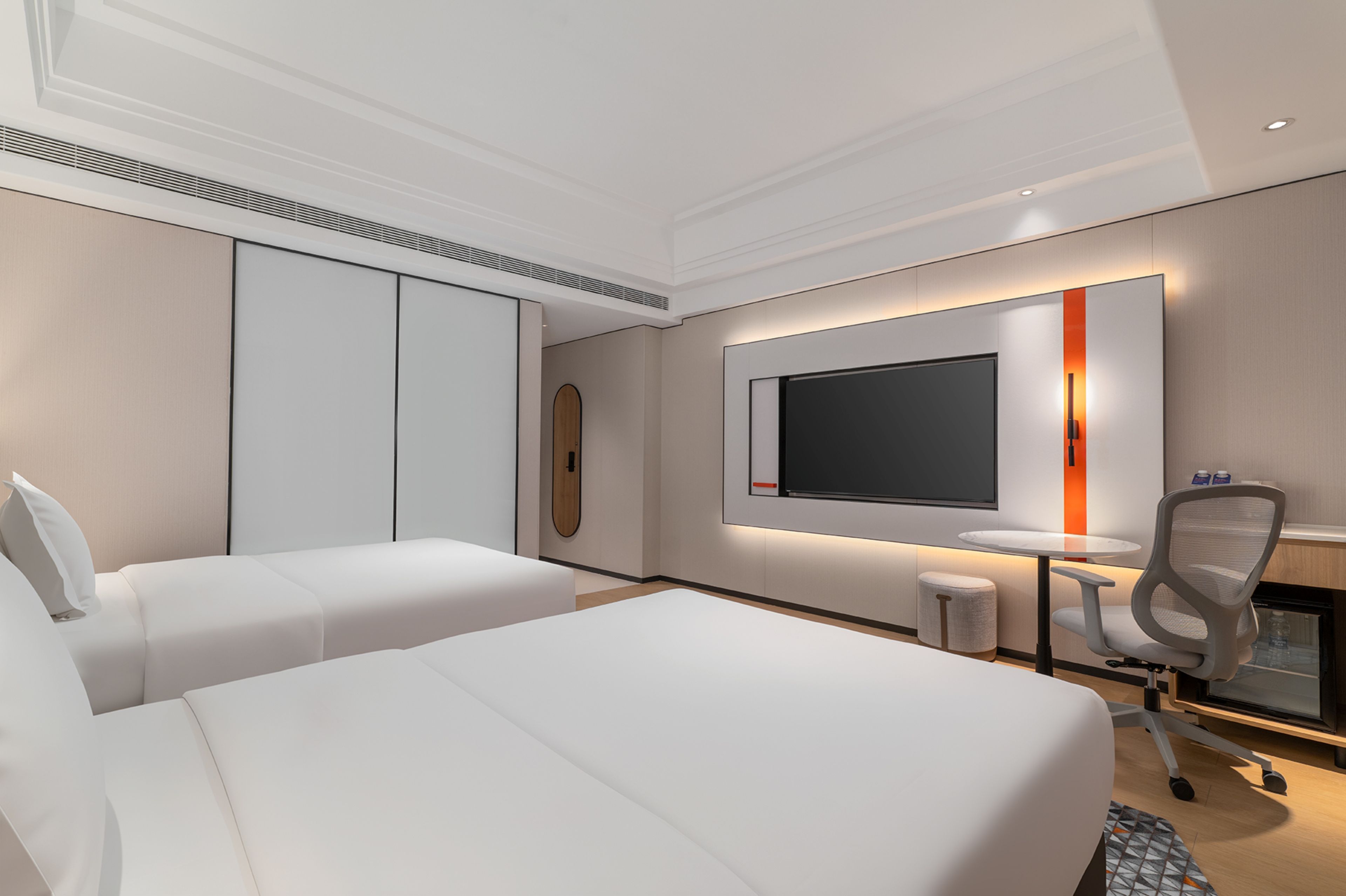A hotel room with two beds, a TV, a desk, and a chair.