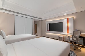 A hotel room with two beds, a TV, a desk, and a chair.