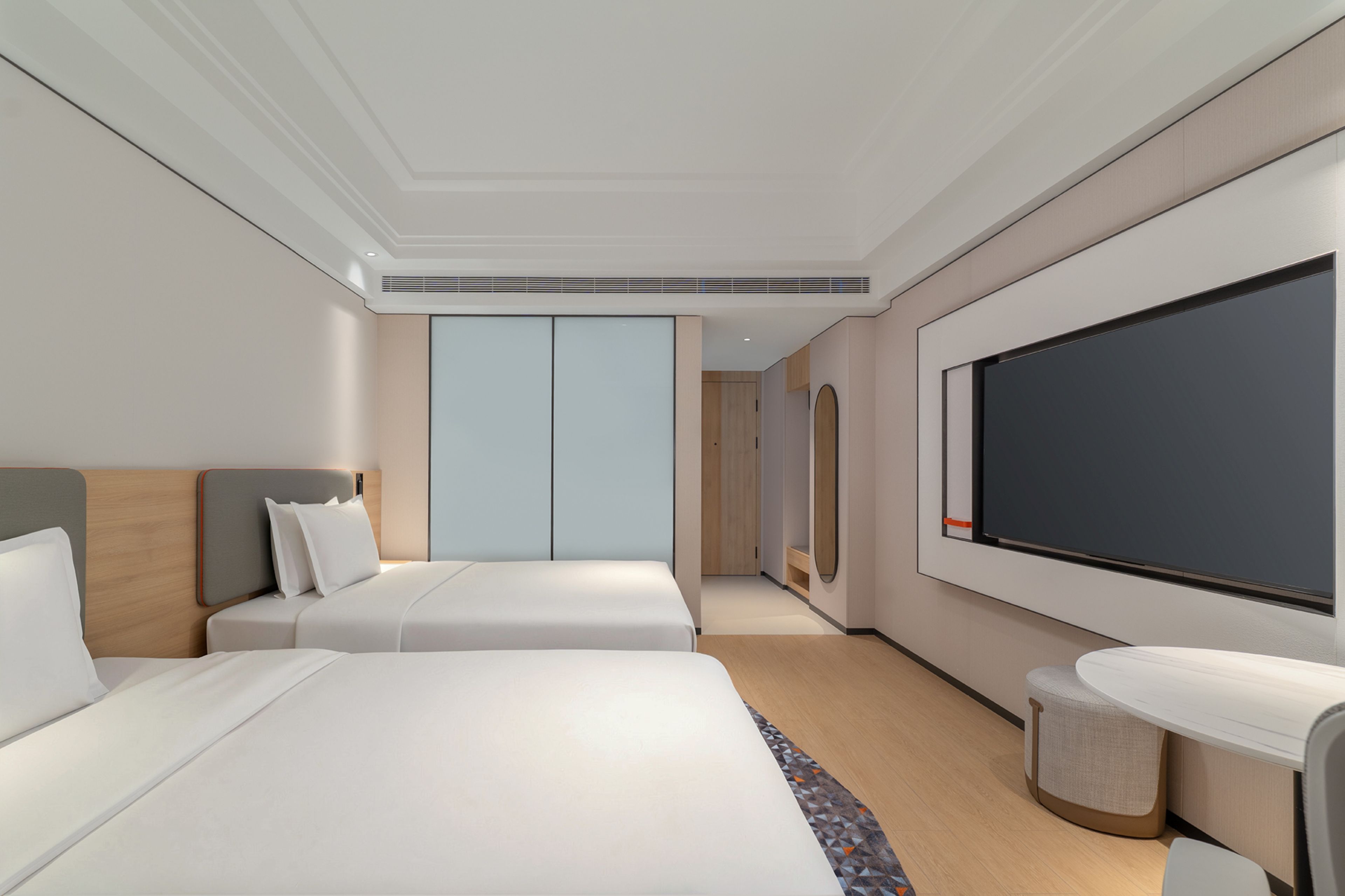 Habitació d'hotel amb dos llits, un televisor de pantalla plana gran i una taula petita.
