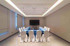 A conference room with a long table, chairs, a projector screen, and a water dispenser. - Holiday Inn Express Qionghai City Center by IHG (Qionghai)