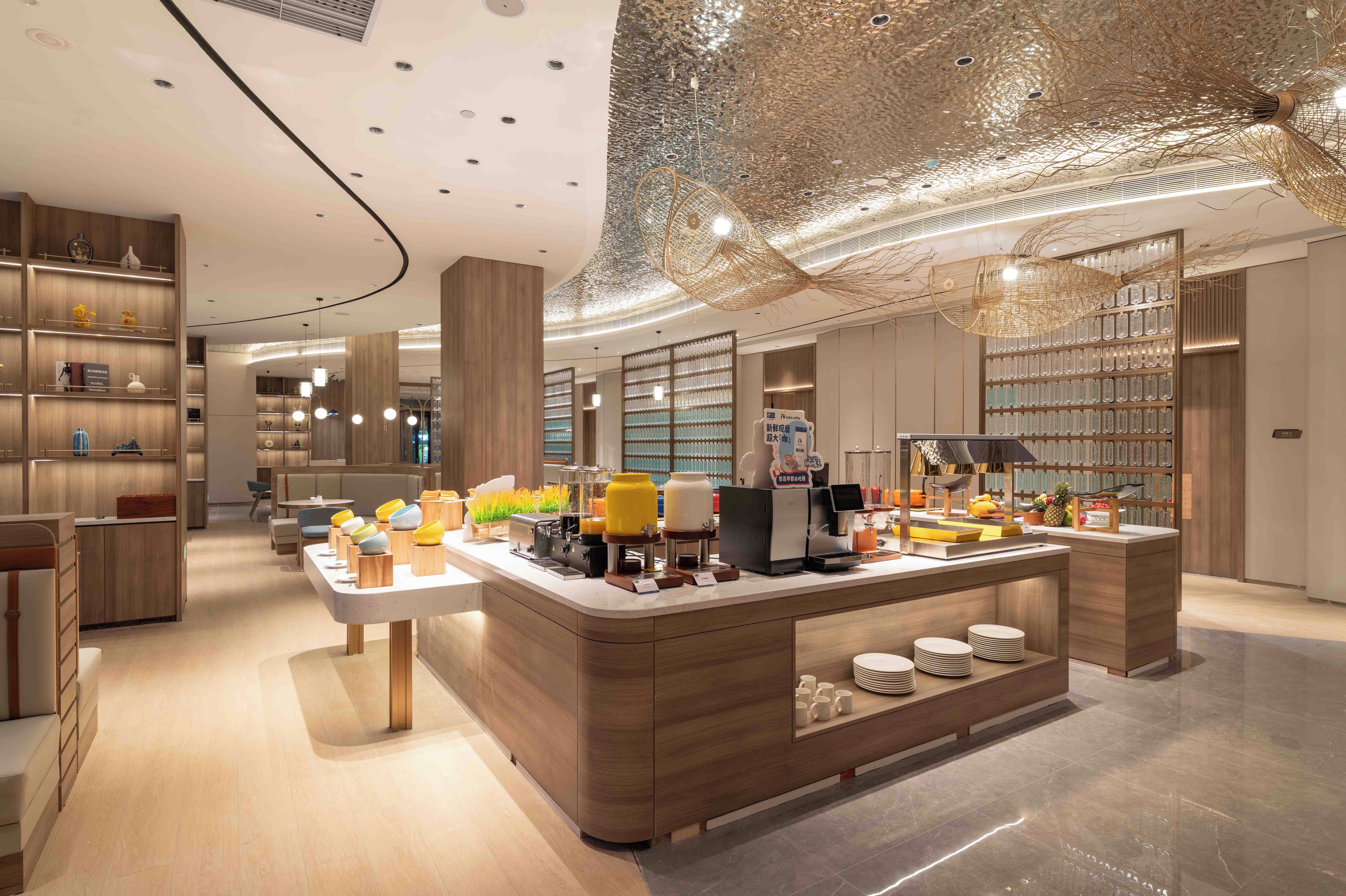 A modern cafe interior with a central counter, seating area, and decorative ceiling.
