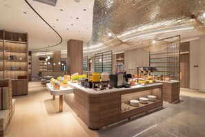 A modern cafe interior with a central counter, seating area, and decorative ceiling. - Holiday Inn Express Qionghai City Center by IHG (Qionghai)