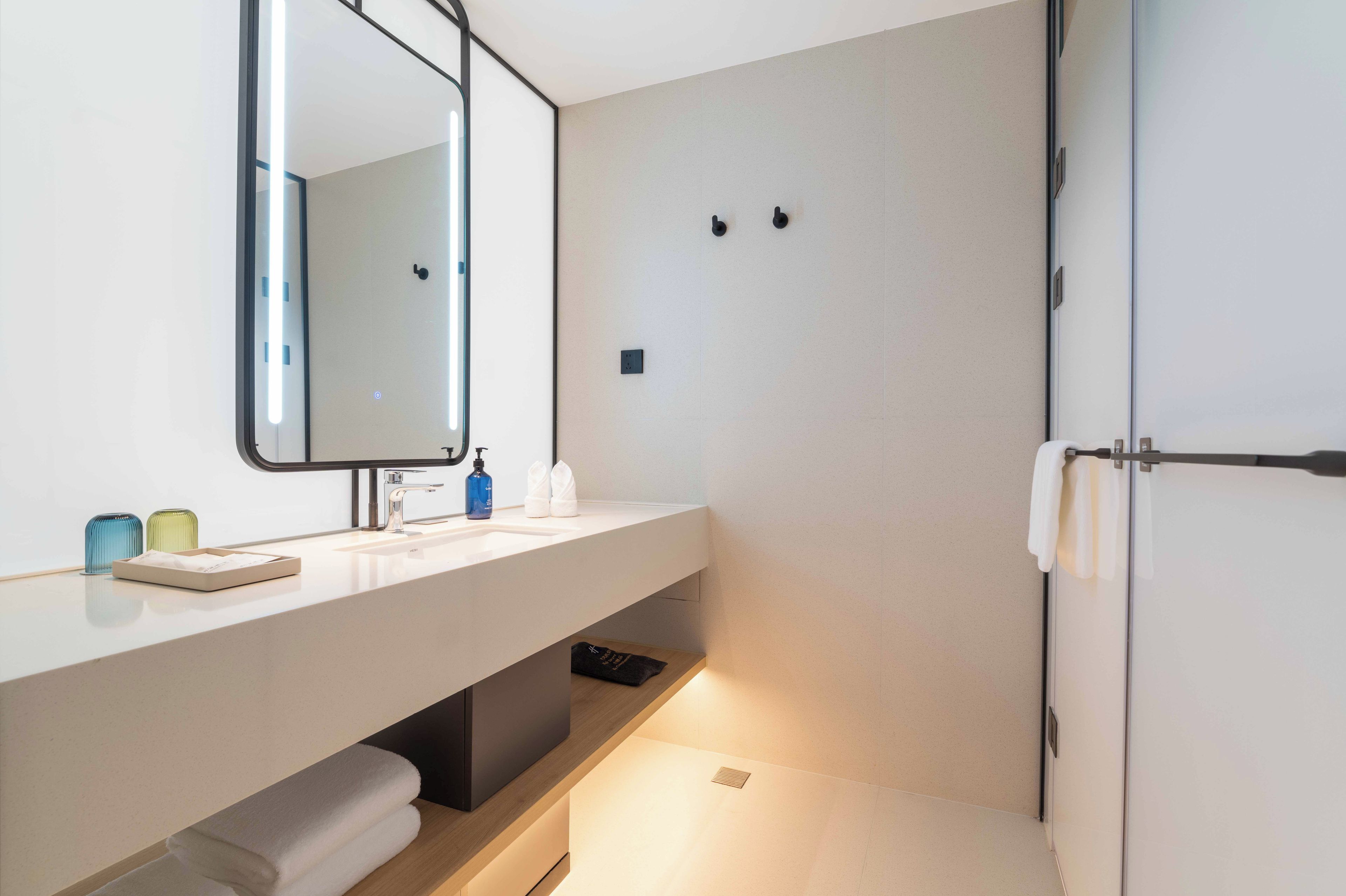 Une salle de bain moderne avec un lavabo blanc, un miroir et un porte-serviettes.