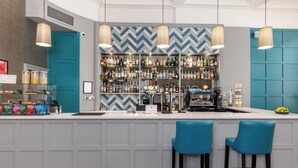 A bar area with a counter, shelves of bottles, two blue bar stools, and a herringbone patterned wall. - 28 York Place (Edinburgh)