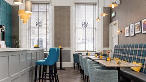 A modern dining area with a long table, blue chairs, and a bench. - 28 York Place (Edinburgh)