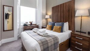 A neatly arranged bedroom with a large bed, bedside tables, a dresser, and a mirror. - 28 York Place (Edinburgh)