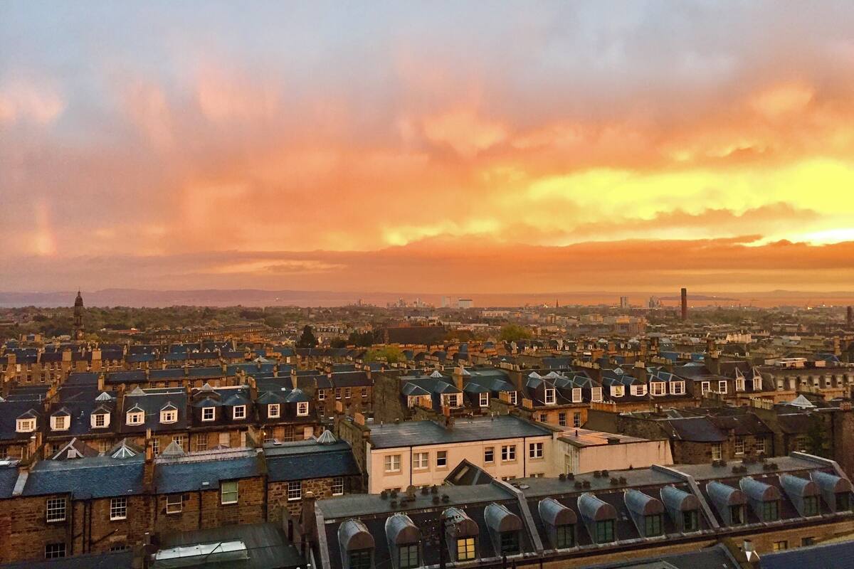 Eine Stadtansicht mit verschiedenen Architekturstilen und einem Himmel in Abendrot.