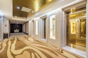 Pasillo de hotel con alfombra estampada, área de recepción y ascensores.