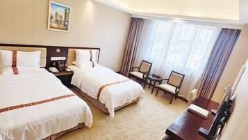 A hotel room with two beds, a desk, a chair, and a small table.
