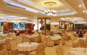 A banquet hall with round tables and chairs, chandeliers, and red decorations. - Longzhu Hotel (Zhaoqing)