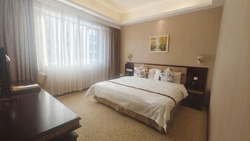 Habitación de hotel con una cama grande, un escritorio, un teléfono y un cuadro en la pared.
