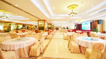 Un salón de banquetes con mesas y sillas redondas, una pantalla grande y candelabros.