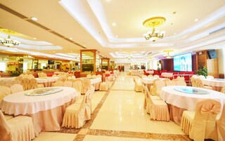 Un salón de banquetes con mesas y sillas redondas, una pantalla grande y candelabros.
