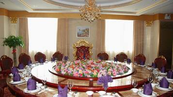 A formal dining room with a round table, ornate chairs, and a chandelier.
