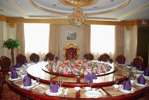 Un comedor formal con una mesa redonda, sillas ornamentadas y una araña.
