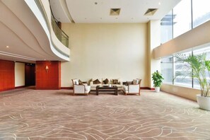 Un hall d’entrée spacieux avec un plafond incurvé, un coin salon avec des canapés, une table basse et une plante en pot.