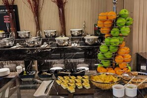A buffet with various food items and a fruit display. - EAC Apartment Hotel (Hangzhou)