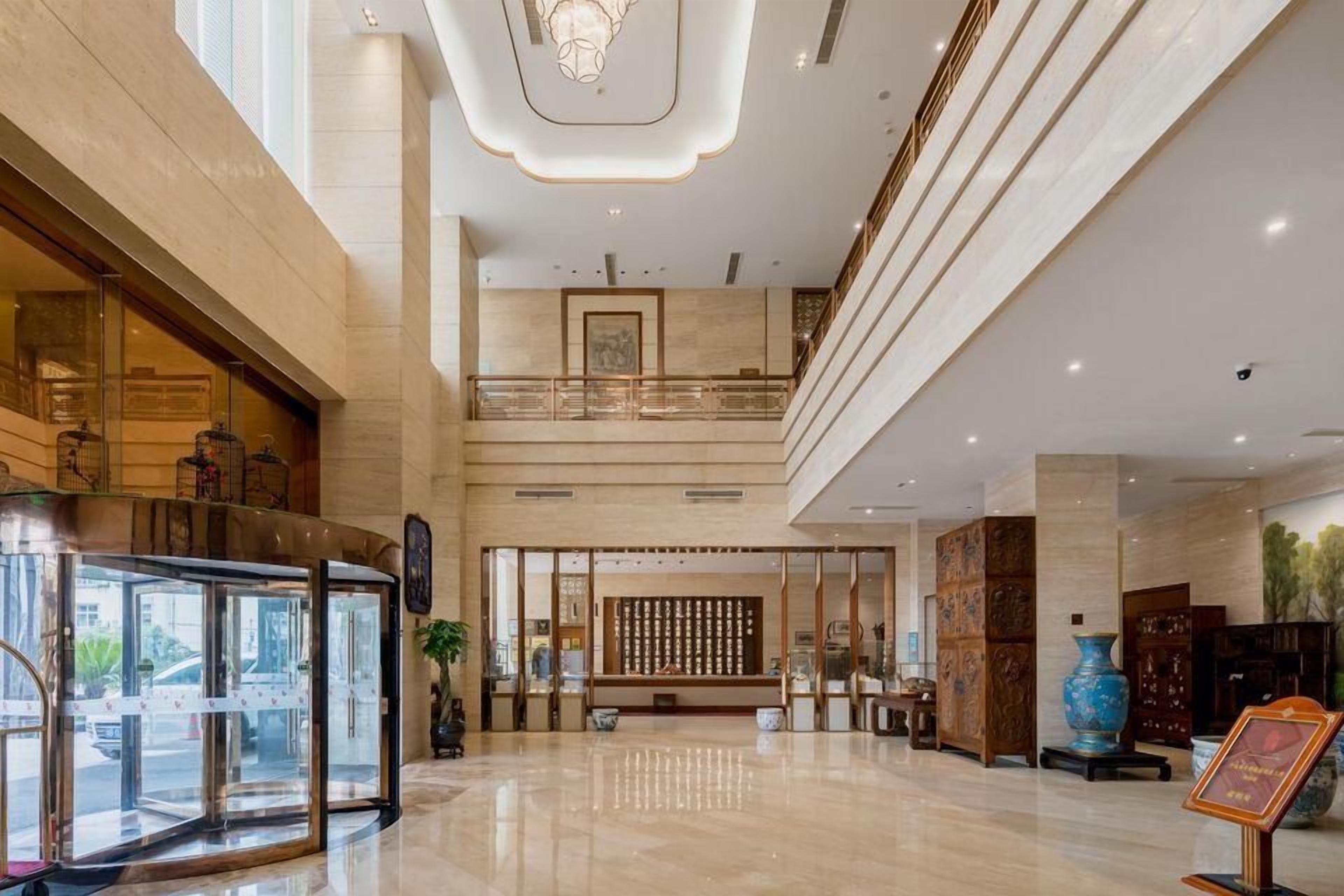 Un hall d’entrée spacieux avec un comptoir d’accueil, un ascenseur en verre et un mur décoratif.