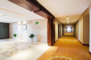 A hotel corridor with a carpeted floor, a wooden door frame, and a wall-mounted sign indicating room number 5F. - Ningbo University Hotel (Ningbo)