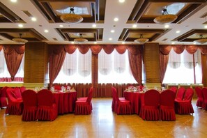 A banquet hall with multiple round tables, red chairs, and large windows with curtains. - Ningbo University Hotel (Ningbo)