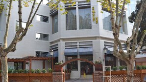 A modern building with a brick facade, large windows, and a wooden pergola with seating. - Ningbo University Hotel (Ningbo)