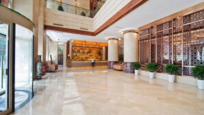 A spacious lobby with a reception desk, a large decorative wall, and potted plants. - Ningbo University Hotel (Ningbo)