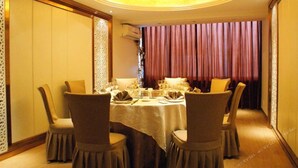 A dining area with a round table set for four, surrounded by chairs. - Ningbo University Hotel (Ningbo)