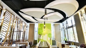 Een modern restaurantinterieur met een lange eettafel, comfortabele zitplaatsen en een opvallend plafondontwerp.
