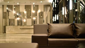 Een moderne lobby met een leren bank en een marmeren receptiebalie.