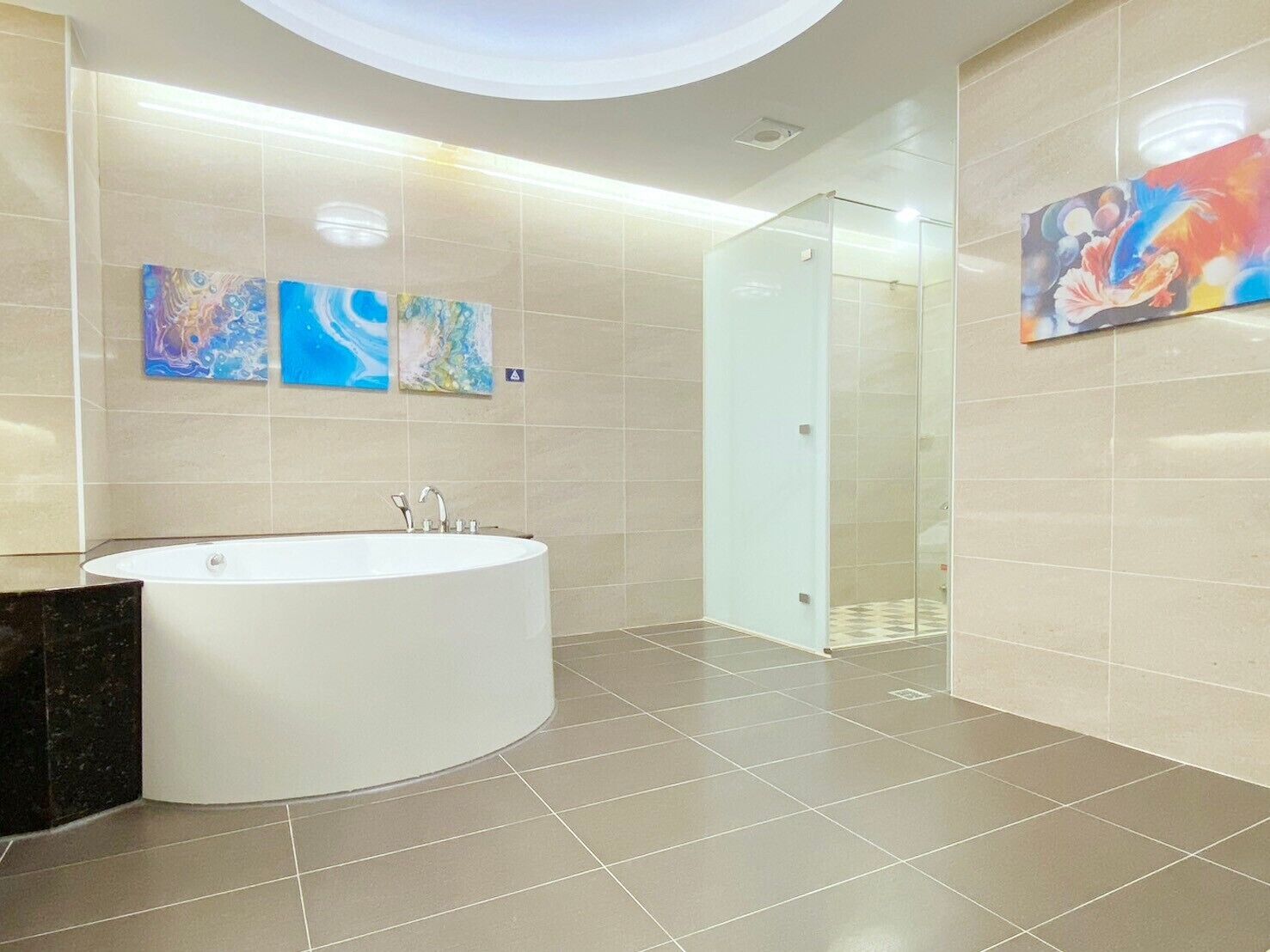 A modern bathroom with a freestanding bathtub, tiled walls, and abstract art.