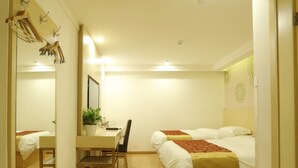 Habitación de hotel con un escritorio de madera, una silla, una cama con una manta roja, una planta en maceta y un espejo.