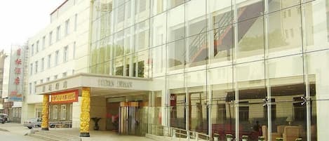 A modern building with large glass windows and a visible entrance area with steps leading up to it.